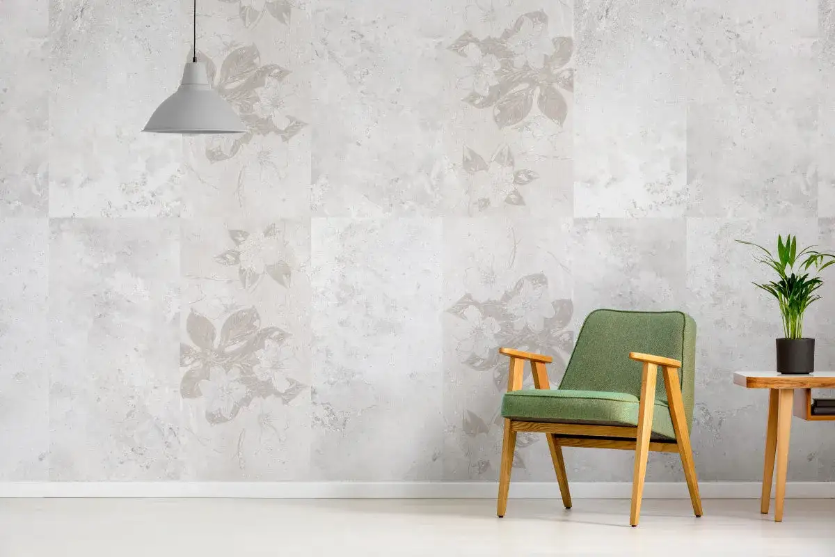 Parete con piastrelle effetto marmo e decori floreali. Sedia verde e tavolino con pianta. Come riconoscere piastrelle prima scelta.