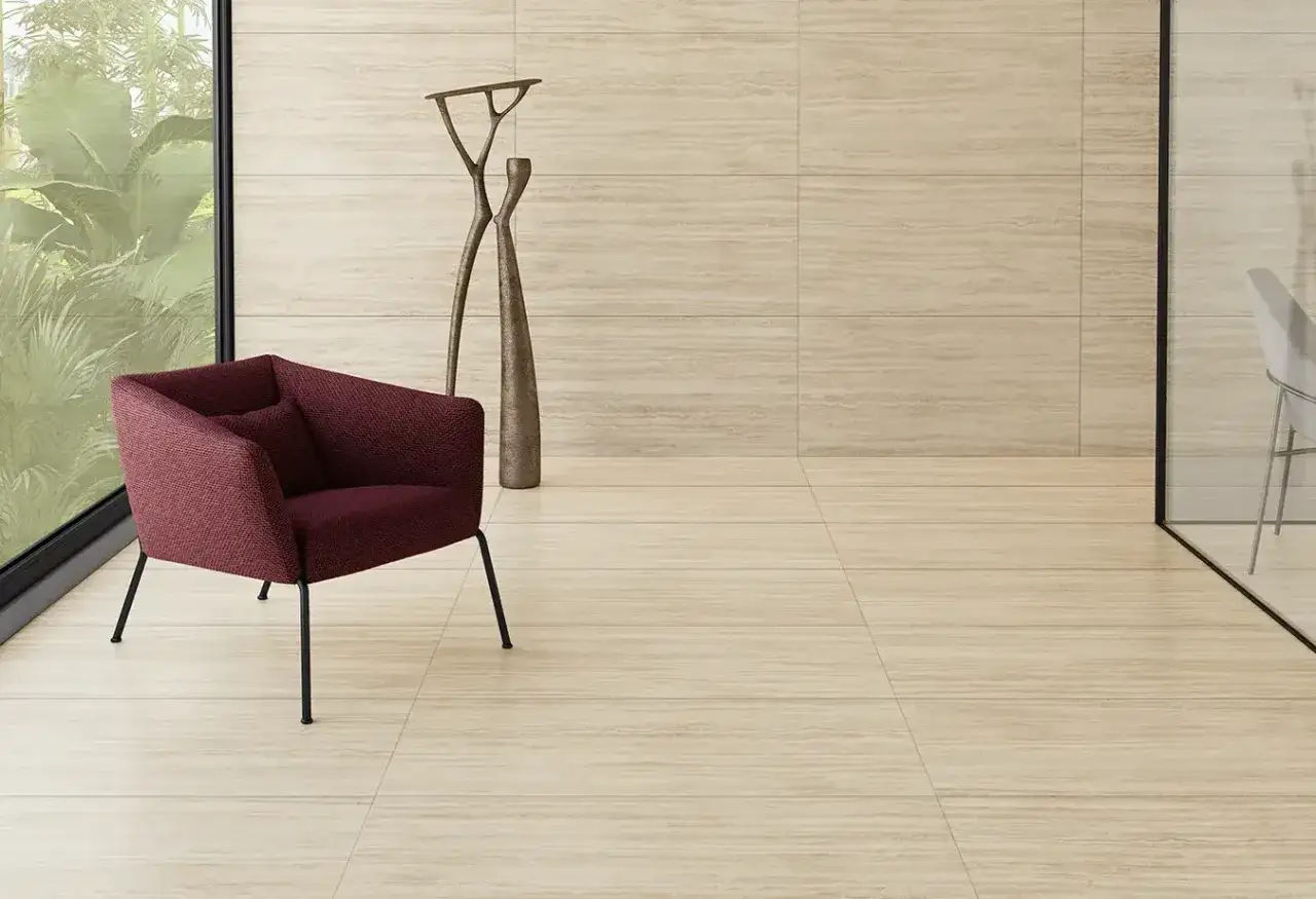 Pavimenti in travertino: eleganza naturale, ma considera la manutenzione. Un salotto moderno con poltrona bordeaux e sculture.