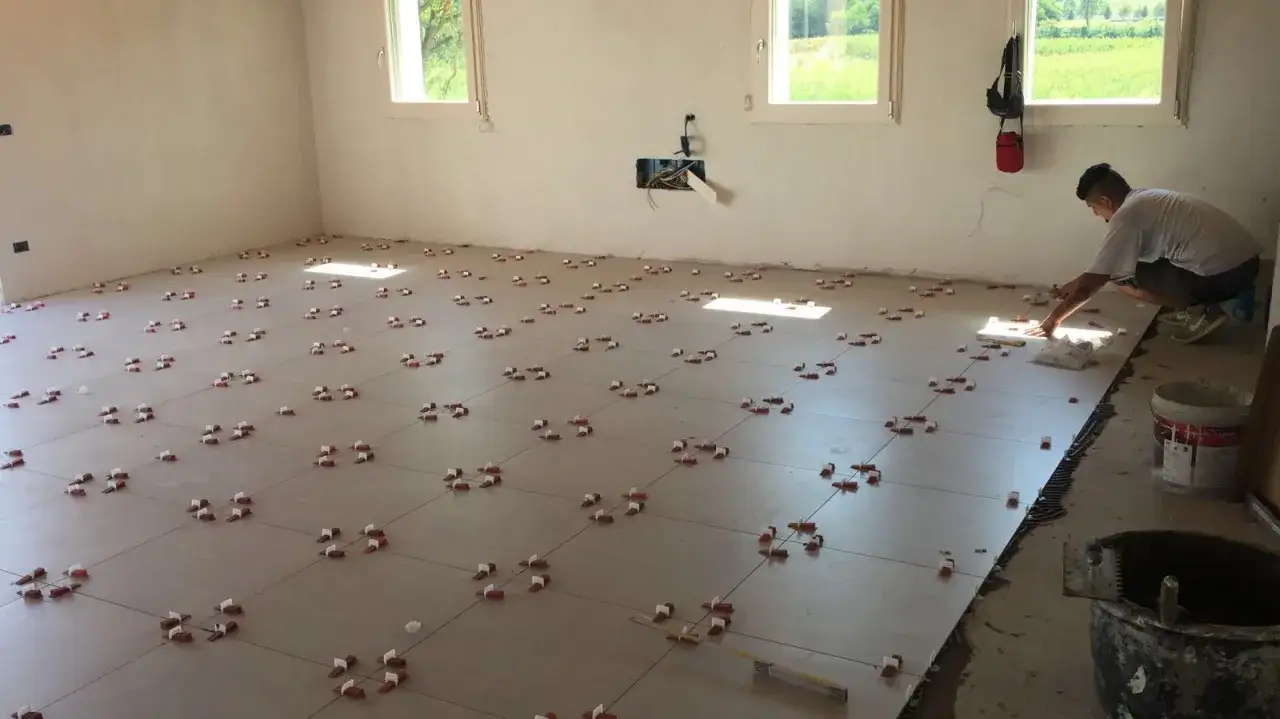 Installazione di piastrelle grandi formati: opinioni positive sul risultato finale. Un operaio posa le lastre con precisione.