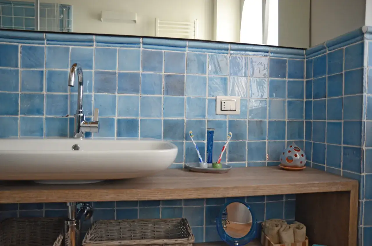 Piastrelle bagno azzurre, perfette da abbinare al cotto per un tocco di colore. Lavabo moderno, porta spazzolini e decorazione a forma di goccia.