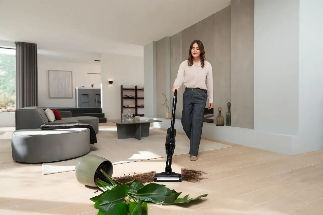 Donna usa aspirapolvere per pulire terra e foglie cadute da un vaso. Ecco come togliere il miele dal pavimento, o meglio, lo sporco!