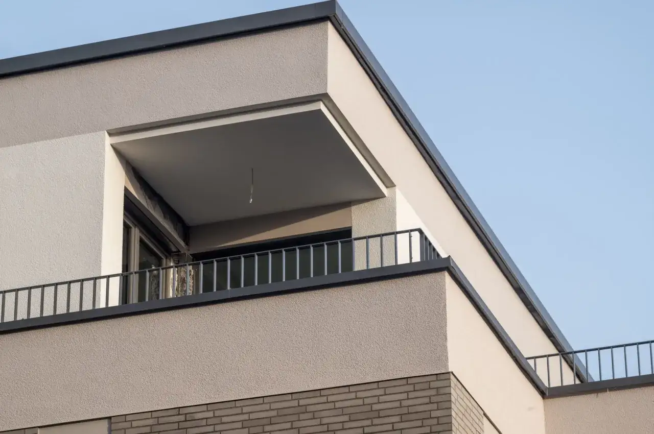 Dettaglio di una pittura facciata esterna moderna con balcone e ringhiera metallica, su sfondo azzurro.
