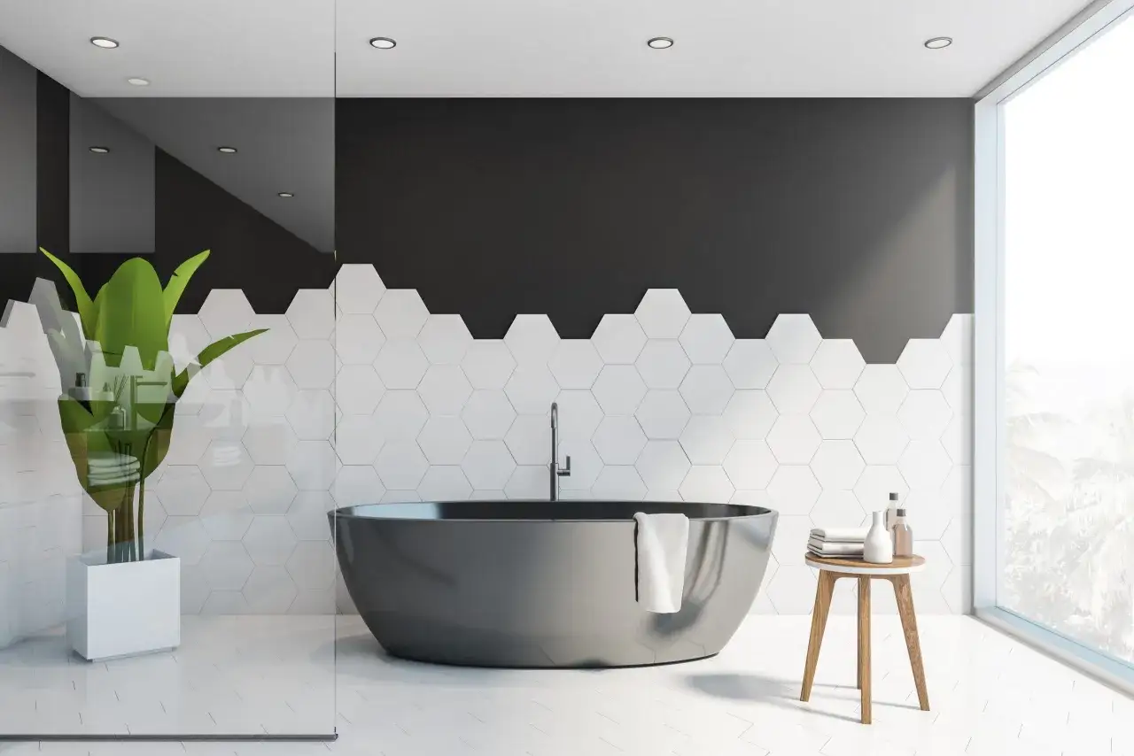 Bagno moderno con vasca grigia, piante verdi e pittura piastrelle bagno esagonali bianche e nere.